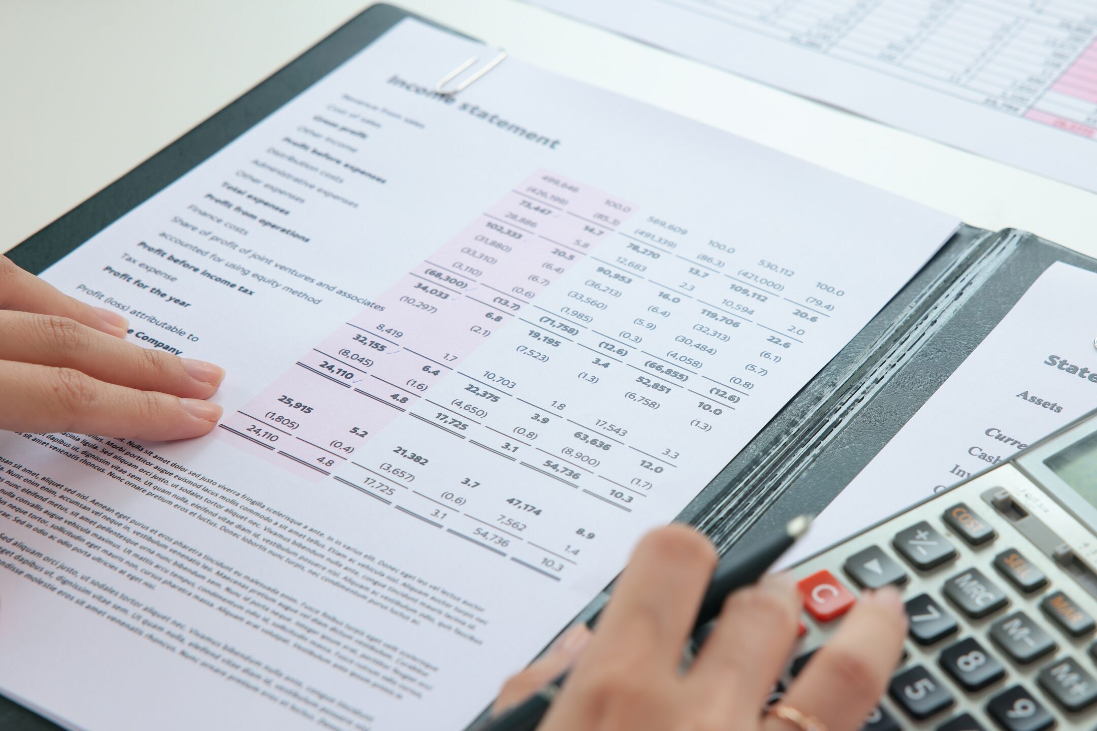Internal,Tax,Audit,Review,Checking,Esg,Data,Risk,In,Balance Person reviewing an income statement with financial figures using a calculator, with documents and a pen on the desk.